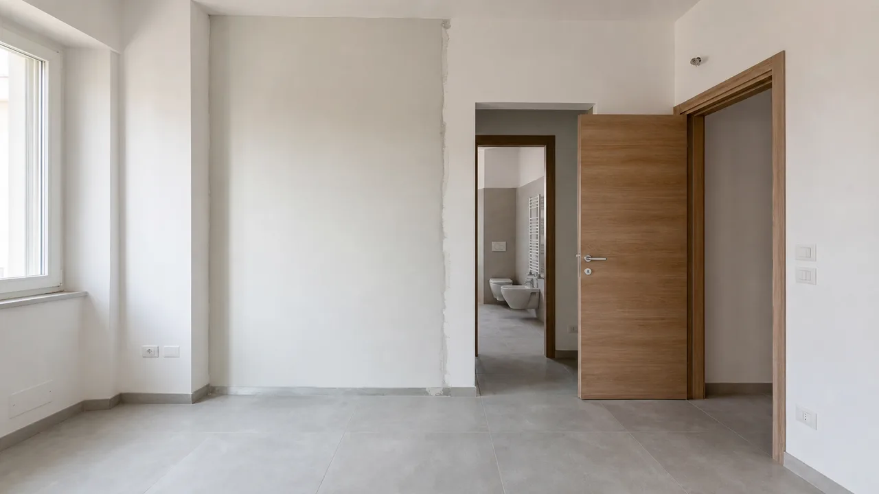 Interno residenziale con tracce di una parete divisoria spostata e un nuovo bagno, modifiche non