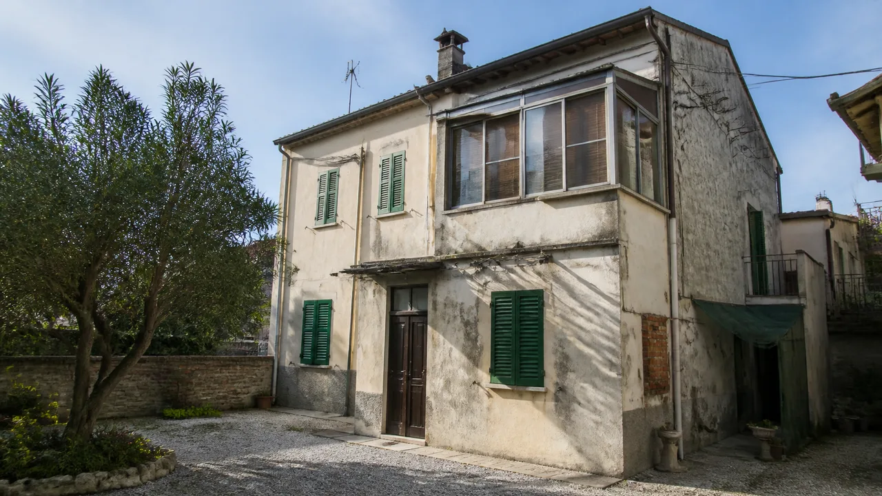 Facciata di una casa datata con verande e aggiunte non uniformi che testimoniano modifiche fatte